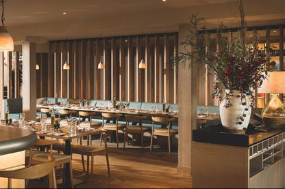Modern restaurant interior with tables, chairs, and decorative elements.